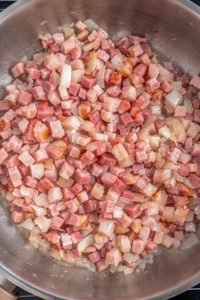 Chopped bacon in a cooking pan with onions.