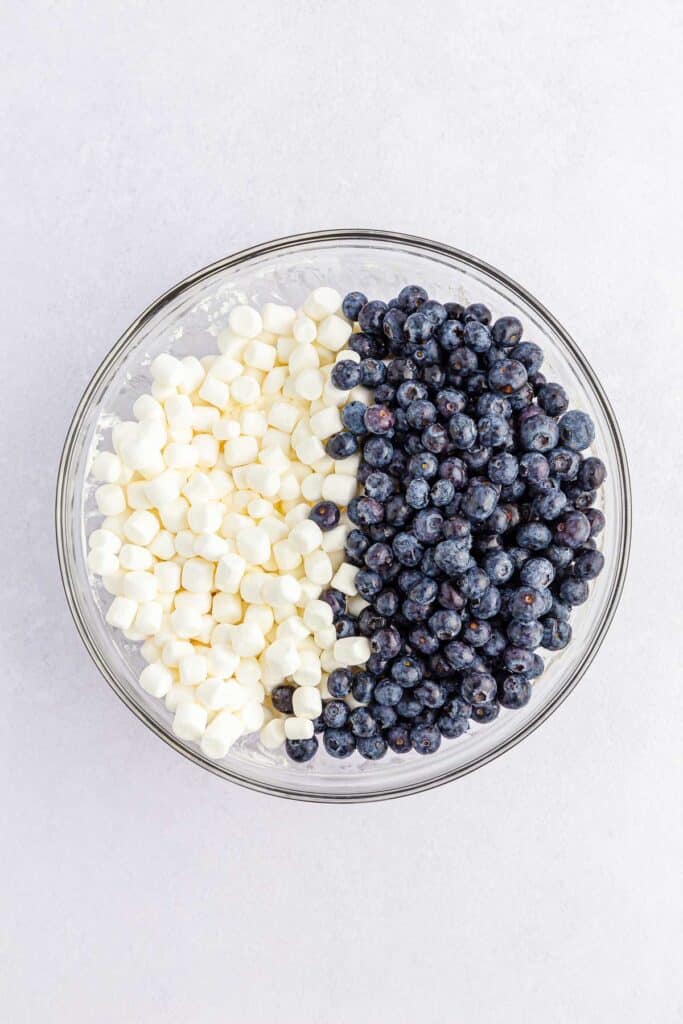Top view of a glass bowl containing fresh blueberries and mini marshmallows.