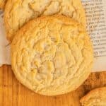 Close-up of two brown sugar cookies resting on a piece of paper on a wooden surface.