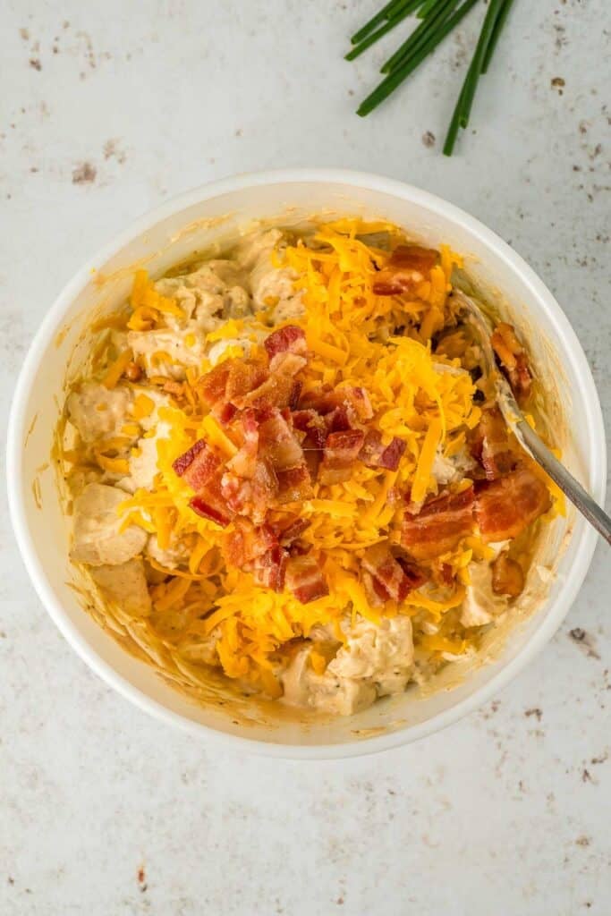 A bowl of ranch potato salad topped with shredded cheese and crumbled bacon.