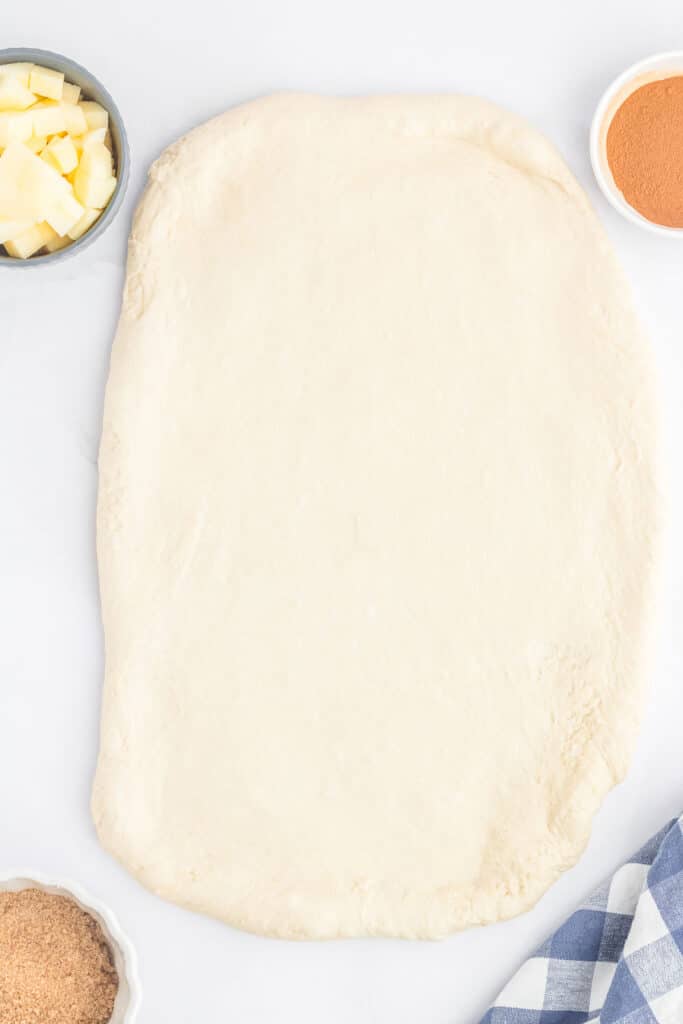 A rolled-out rectangular dough on a white countertop.