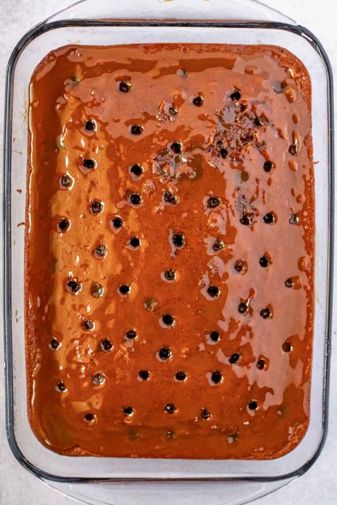 A rectangular glass baking dish with a chocolate cake with caramel sauce poured overtop.