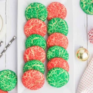 A white rectangular plate with an arrangement of red and green soft sugar cookies.