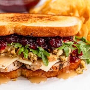 A sandwich with turkey, cheese, dressing, gravy, and cranberry sauce on toasted bread, with gravy.
