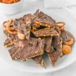 A plate of chocolate pretzel bark with small pretzels and caramel drizzles.