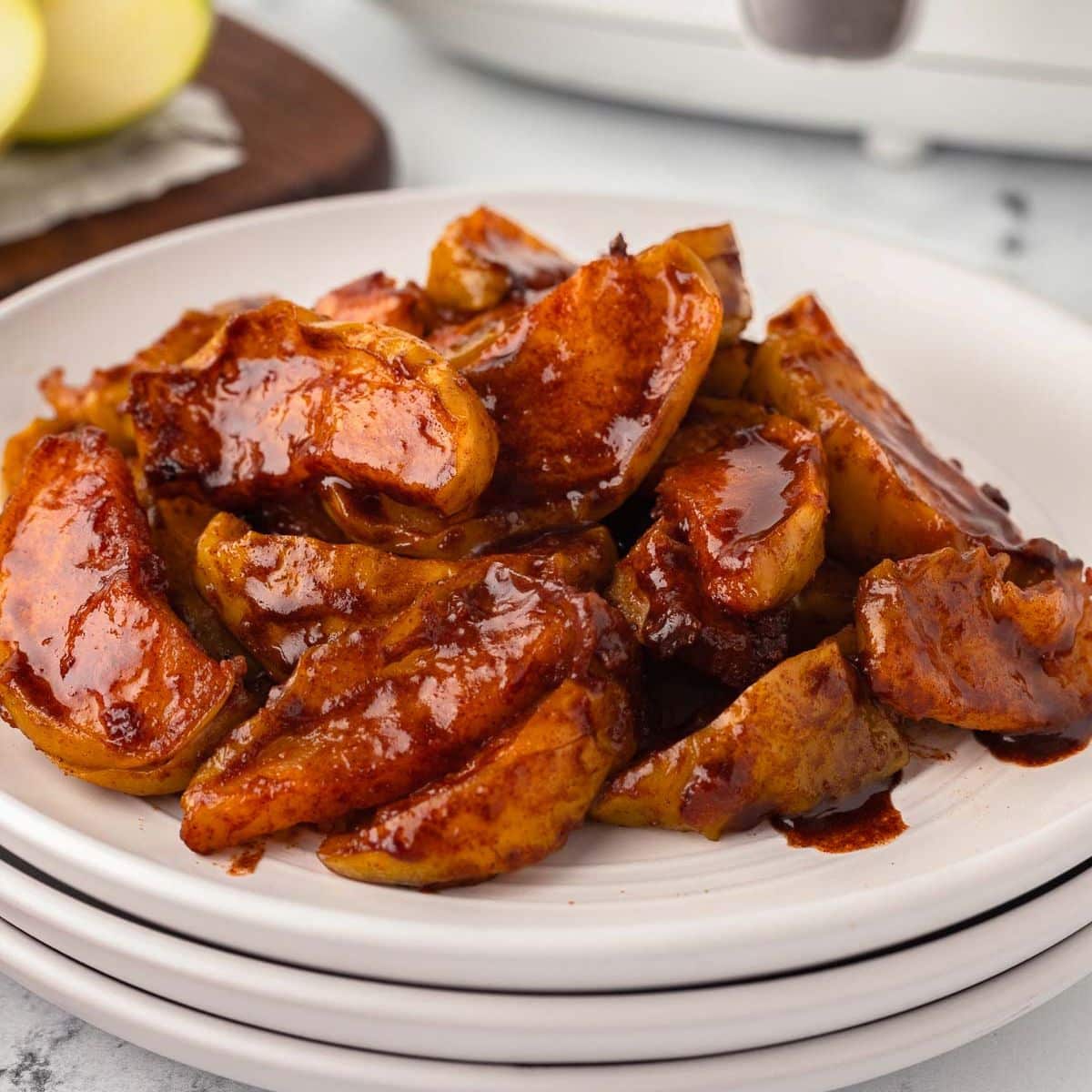 A plate of sliced air fryer apples coated in a brown caramel sauce.