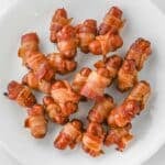 A plate with several bacon-wrapped cocktail sausages.