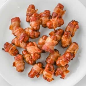 A plate with several bacon-wrapped cocktail sausages.