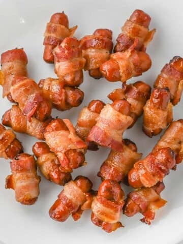 A plate with several bacon-wrapped cocktail sausages.