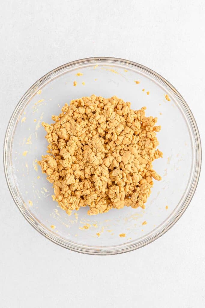 A glass bowl containing a peanut butter dough mixture.