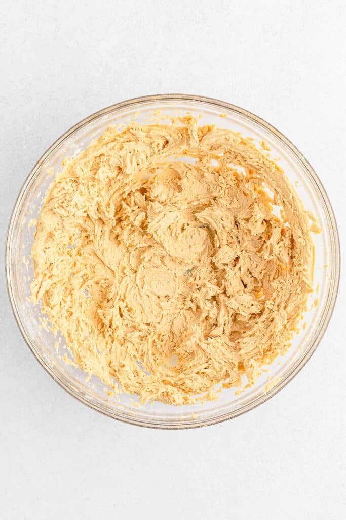 A glass bowl filled with a creamy peanut butter frosting.