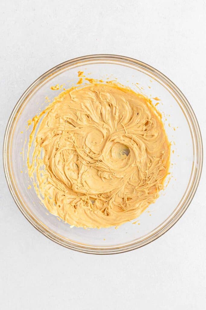 A glass bowl filled creamy peanut butter and butter mixed together.