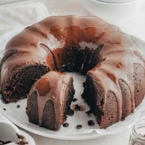 Chocolate Sweet Potato Cake with a chocolate frosting, partially sliced, placed on a parchment-lined plate.