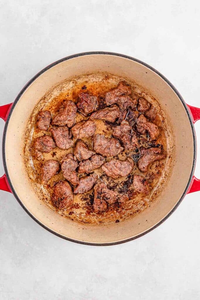 Chunks of cooked lamb in a red pot.