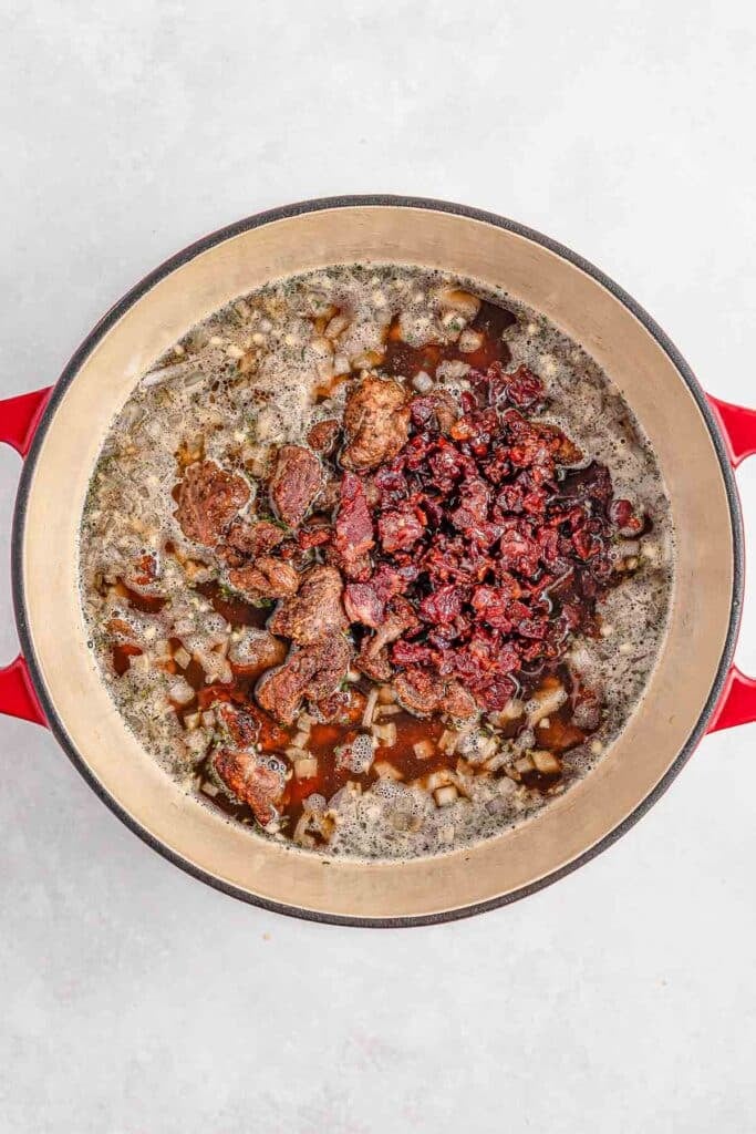 Seared lamb and bacon simmering in a beef broth and red wine mixture