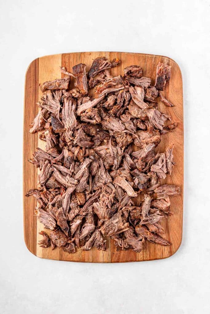 Shredded short rib on a wooden cutting board.