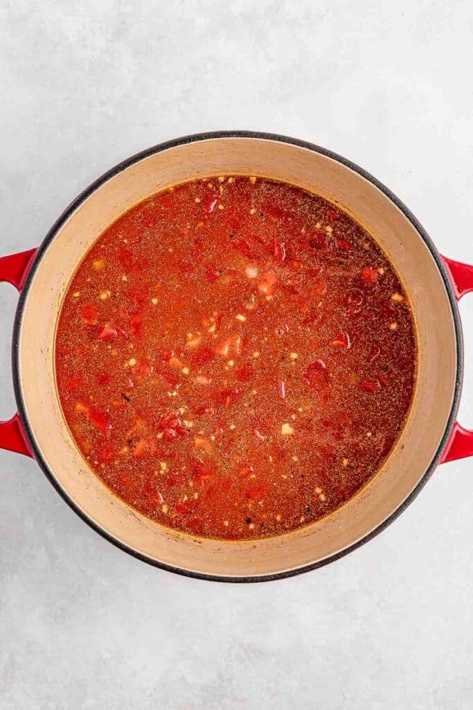 A red pot filled with a the tomato sauce mixture.