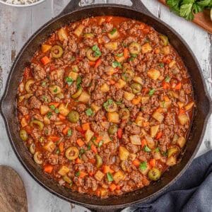 A skillet with Mexican Picadillo topped with cilantro on a grey table ready to be served.