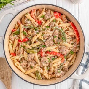 A dutch oven filled with rasta pasta with caribbean jerk chicken.
