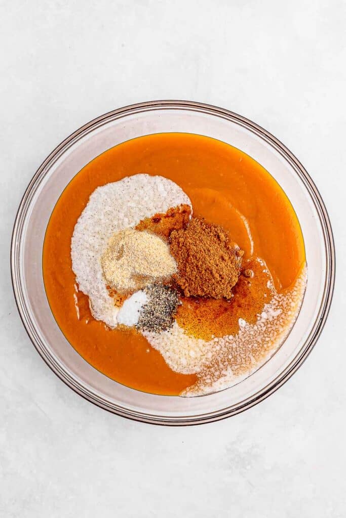A glass bowl filled with the hot sauce, honey, butter, cayenne pepper, garlic powder, salt, and black pepper ready to be mixed.