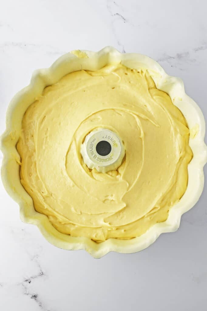 A bundt pan filled with another top layer of smooth, yellow cake batter.
