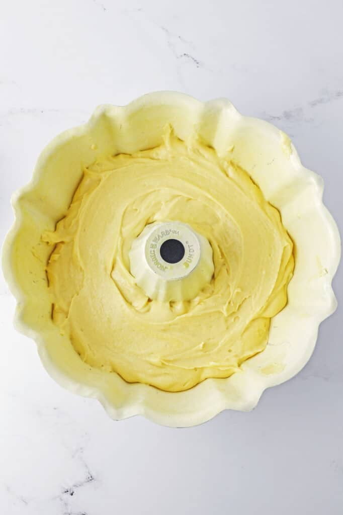 A bundt pan filled with smooth, yellow cake batter.