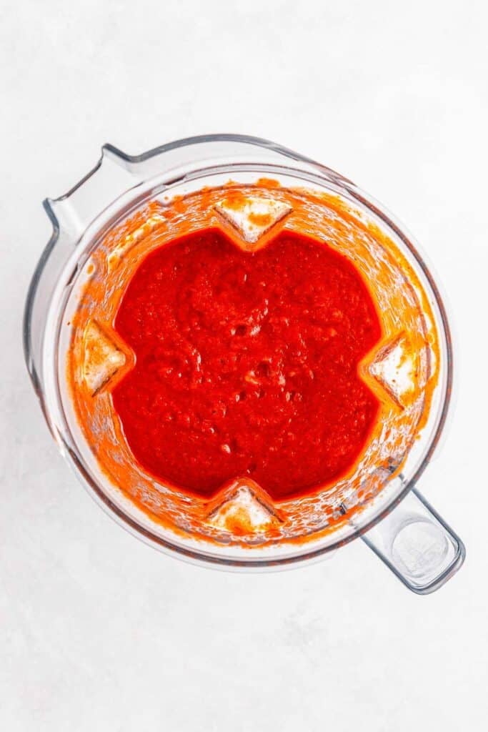 A blender filled with red tomato sauce.
