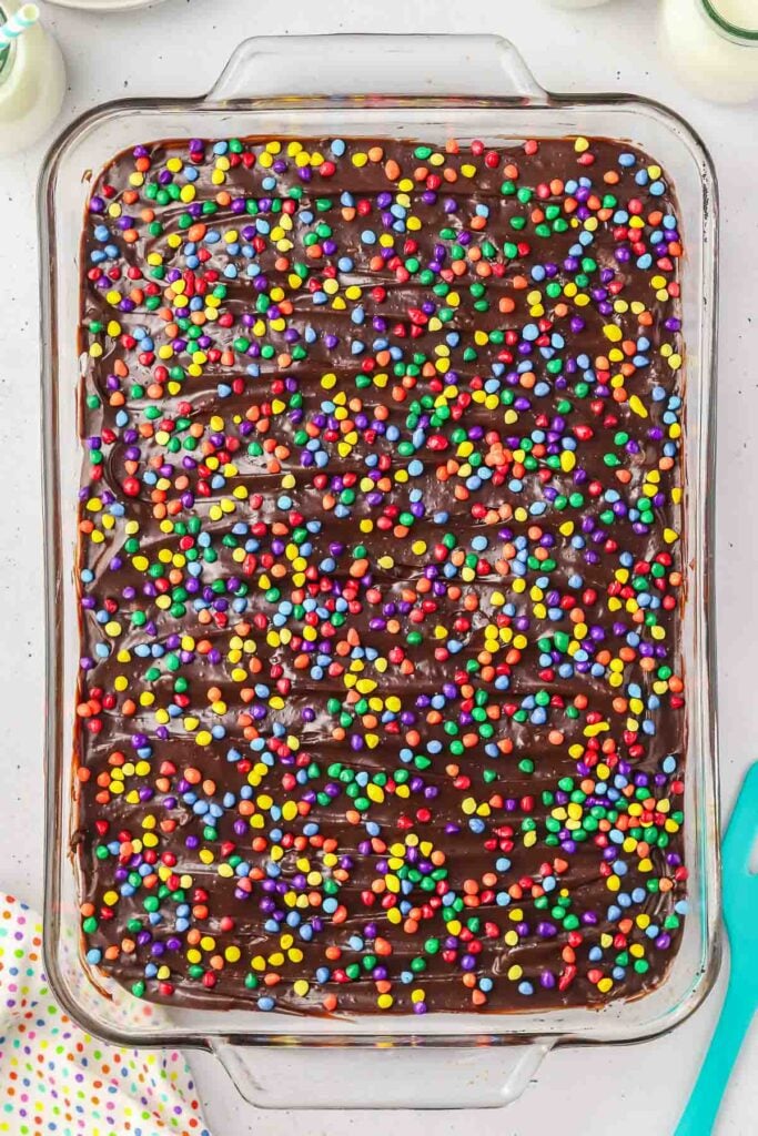 Cosmic brownies in a glass baking dish, topped with chocolate frosting and colorful mini chocolate chips.
