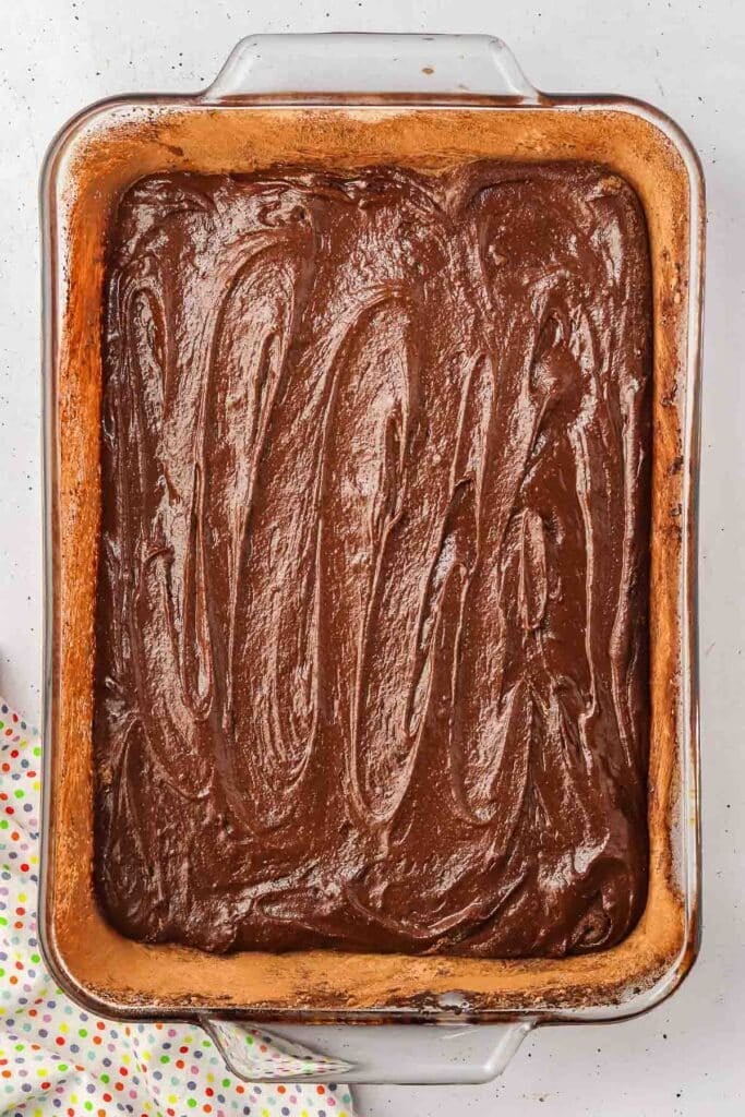 A rectangular glass baking dish filled with chocolate batter, spread evenly, ready to be baked.