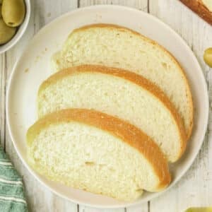 Three slices of italian bread are arranged on a white plate.