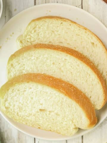 Three slices of italian bread are arranged on a white plate.