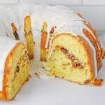 A sliced bundt cake with a white glaze and a cinnamon streusel filling.