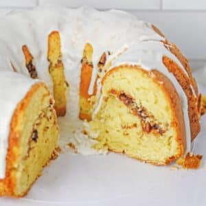 A sliced bundt cake with a white glaze and a cinnamon streusel filling.