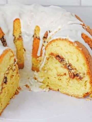 A sliced bundt cake with a white glaze and a cinnamon streusel filling.