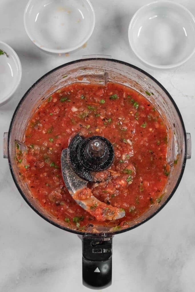 Overhead view of a food processor filled with freshly blended salsa.