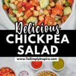 A bowl of chickpea salad with chopped cucumbers, tomatoes, red bell peppers, and red onions on a white surface.