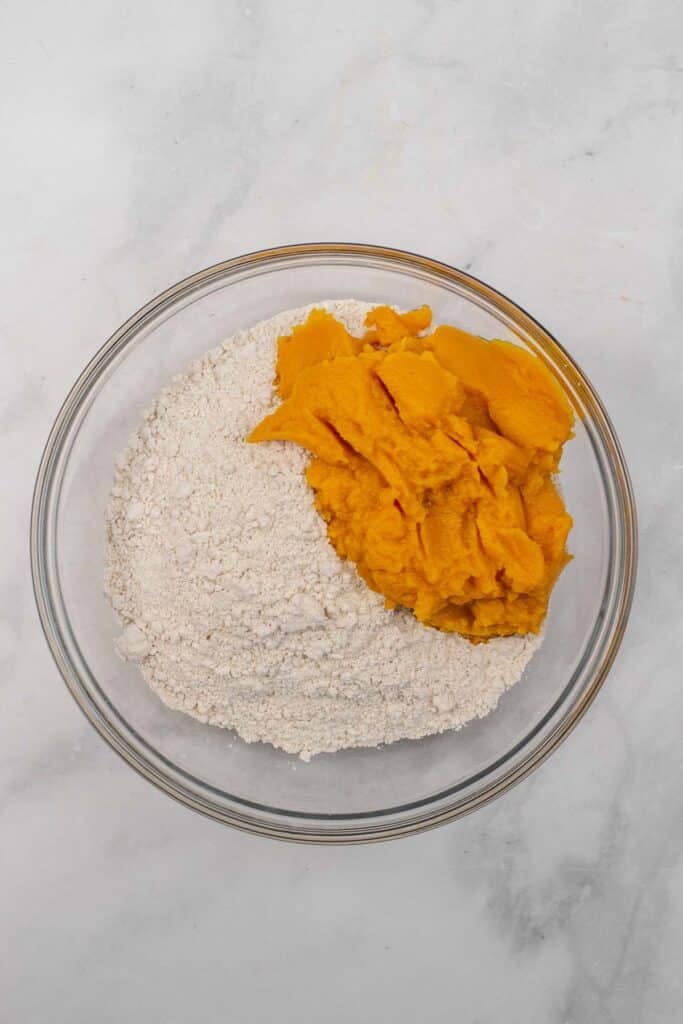 A glass bowl containing spice cake mix and pumpkin puree.