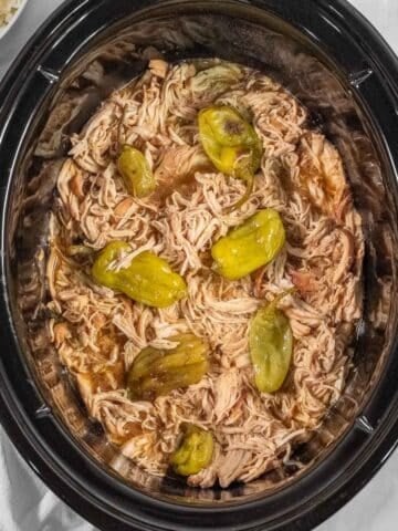 Shredded Mississippi chicken and peperoncini peppers in a slow cooker
