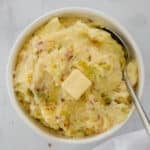 Bowl of colcannon Irish potatoes with cabbage and a slice of butter on top.