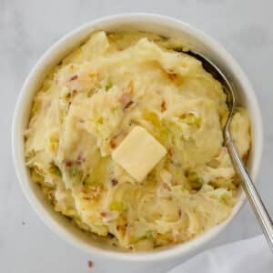 Bowl of colcannon Irish potatoes with cabbage and a slice of butter on top.