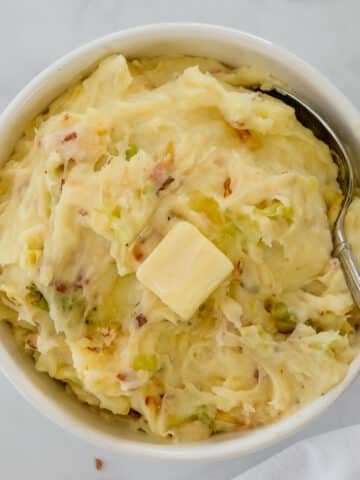 Bowl of colcannon Irish potatoes with cabbage and a slice of butter on top.