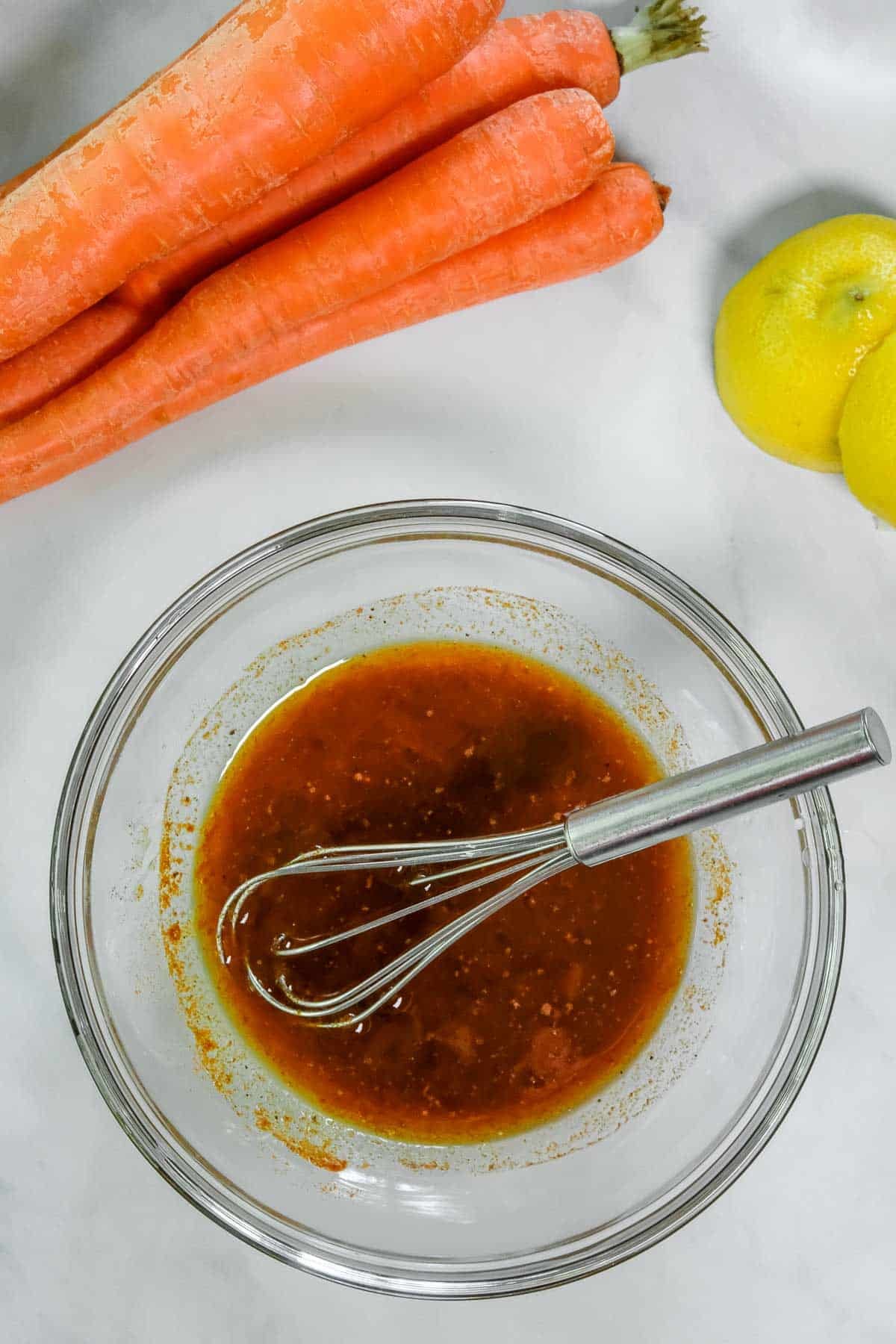 A small bowl with whisked together olive oil, lemon juice, cumin, paprika, cinnamon, salt, black pepper.