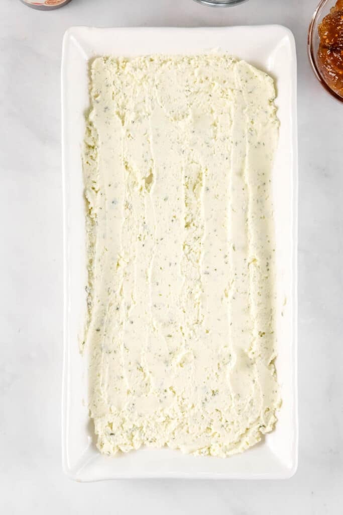 A rectangular white dish filled boursin cheese spread evenly.