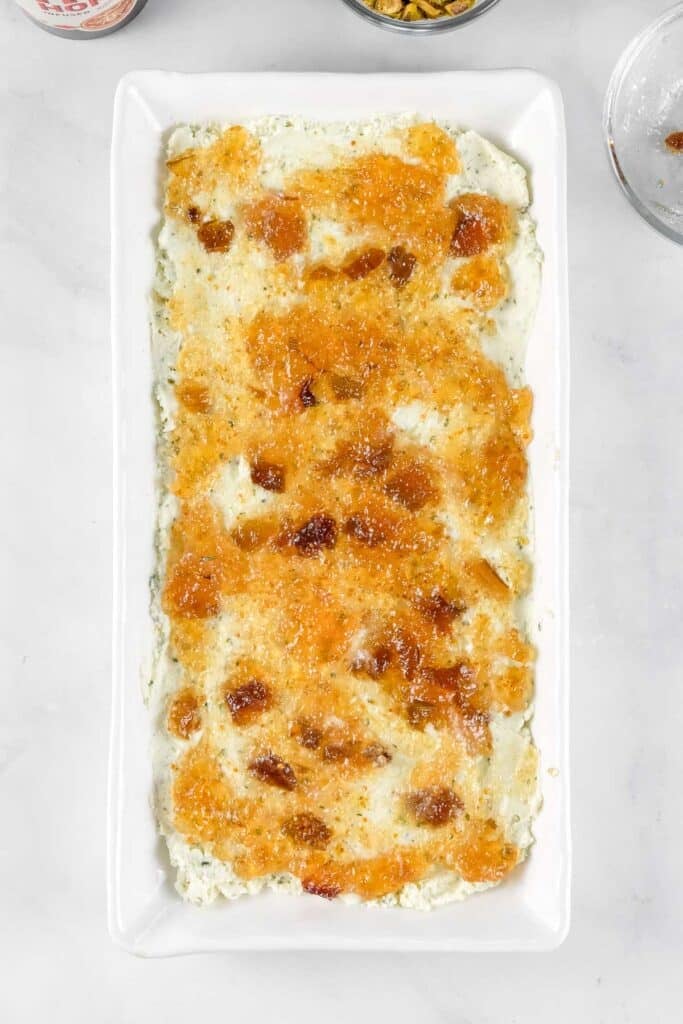 Rectangular white dish with a layer of bousin cheese spread across the dish with a layer of hot honey and fig preserves spread atop.