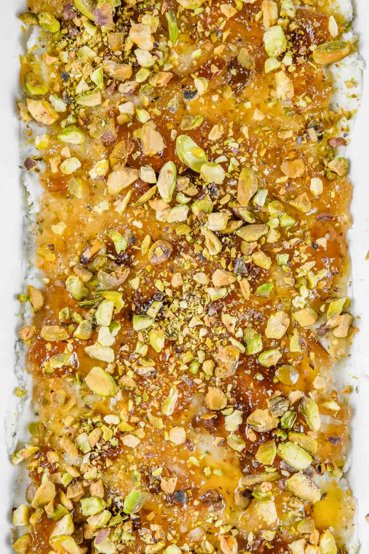 Rectangular white dish of Boursin cheese dip topped with chopped pistachios.