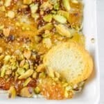 Rectangular white dish of Boursin cheese dip topped with chopped pistachios.
