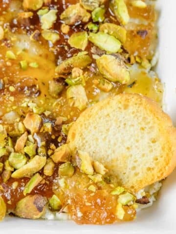 Rectangular white dish of Boursin cheese dip topped with chopped pistachios.