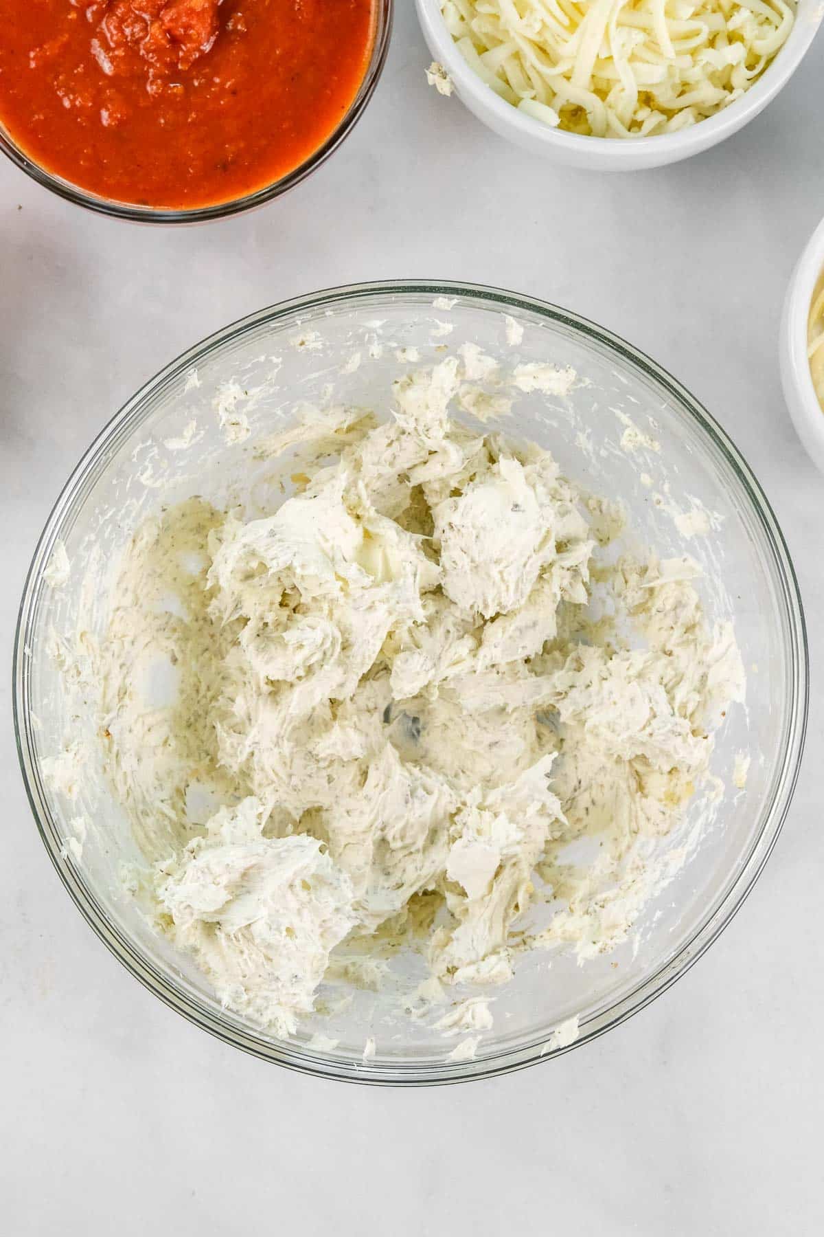 A glass bowl containing a cream cheese mixture.